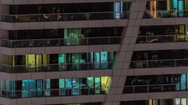 Apartman binasının parlayan pencerelerinin gece görüşü. Işıklı ve hareketli yüksek gökdelenler