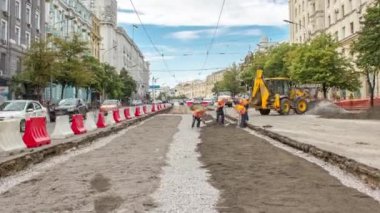 Buldozer hareket eder ve zamanı gelince toprağı ve molozu yayar. Tramvay raylarının yeniden inşasında turuncu üniformalı işçiler. Sokakta trafik vardı. Yol yapım aşamasında.