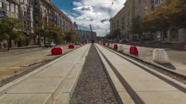 Yol inşaatı zamanına vinçle beton plakalar yerleştiriliyor. Şehir merkezinde yoğun sokak trafiği var. Şehir caddesindeki tramvay raylarının yeniden inşası