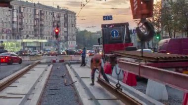 Kamyon timelapse dan portakal inşaat teleskopik Vinçler-Mobil vinç kaldırma tramvay rayları. Kavganın ve üniforma ile sanayi işçileri. Sokak şehir tramvay yeniden inşası izler