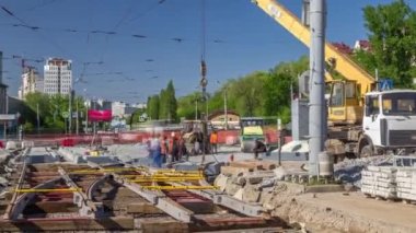 Yol inşaatı zamanına vinçle beton plakalar ve raylar yerleştiriliyor. Şapkalı ve üniformalı endüstriyel işçiler. Şehir caddesindeki tramvay raylarının yeniden inşası