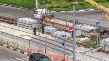 Büyük boy kamyondan beton plakaları yüklemek ve indirmek için vinç, uzun bir yükleme platformuyla birlikte, bir yol inşaatı alanının hava zaman tünelinde duruyor.