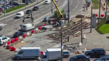 Yol inşaatı alanındaki hava zaman ayarına vinçle beton plakalar yerleştiriliyor. Şapkalı ve üniformalı endüstriyel işçiler. Şehir caddesindeki tramvay raylarının yeniden inşası