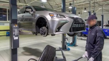 Araba tamircisi vidaları söküyor ve tamir istasyonunda pnömatik ingiliz anahtarıyla kaldırılan otomobilin vidalarını söküyor. Tramvayda tekerlekleri hareket ettirir