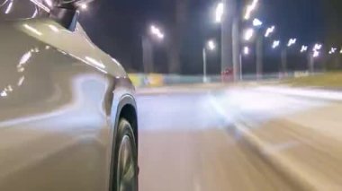 Zaman ayarlı sürüşler caddelerde yüksek hızda sürerken zaman ayarlı süratli süratler. Gece şehir yolunda kaydırma hareketli gümüş arabanın yanından görüntüle