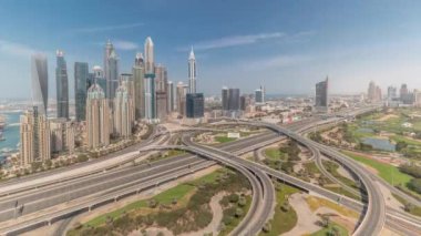 Dubai Marina karayolu kavşağındaki panorama spagetti kavşağı tüm gün boyunca devam etti. Arka planda hızla hareket eden gölgeli en uzun gökdelenler. JLT bölgesinden hava görüntüsü. Bulutlu gökyüzü