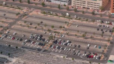 Alışveriş merkezinin yakınındaki büyük otopark birçok araba tarafından dolduruluyor. Bütün gün hareket eden gölgelerle araçlar girip çıkıyor.