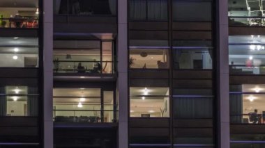 Modern ofisteki büyük parlayan pencereler ve konut binaları gece saatlerine göre ayarlanıyor, pencereler ışık saçıyor. Evde çalışma yeri