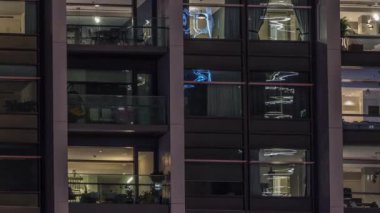 Modern ofisteki büyük parlayan pencereler ve konut binaları gece saatlerine göre ayarlanıyor, pencereler ışık saçıyor. Evde çalışma yeri
