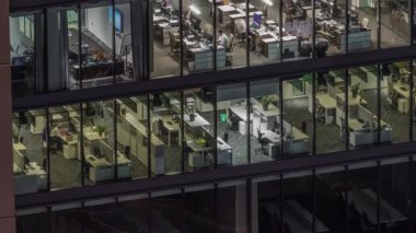 Modern ofis binalarındaki büyük parlayan pencereler geceleri zaman ayarlı, sıra sıra parlıyor. Açık alan çalışma yerleri