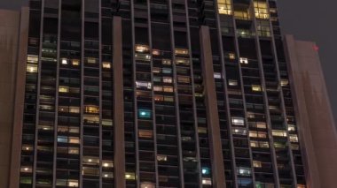 Modern ofis ve konut binalarındaki büyük parlayan pencereler gece görüş zamanlamasına bakar, pencereler ışık saçar.