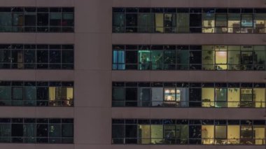 Modern apartmanlardaki pencere ışıkları geceleri zaman ayarlı. İçinde aydınlık odalar olan çok katlı gökdelenler.