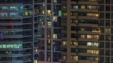 Modern ofisteki birçok pencere ışığı ve konut binaları geceleri zaman ayarlı. İçinde aydınlık odalar olan çok katlı gökdelenler.