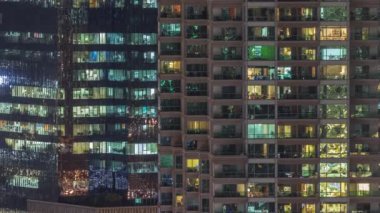 Apartman pencereleri ve ofis binaları, evlerin pencerelerinden gelen ışık. Parlak odalı şehrin akşam manzarası