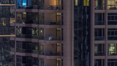 Gece vakitlerinde apartmanların pencereleri, evlerin pencerelerinden gelen ışık. Parlak odalı şehrin akşam manzarası