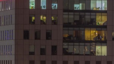 Geceleri ofis binalarının pencereleri, gökdelenlerin pencerelerinden gelen ışık. Parlak kuleleri olan şehrin akşam manzarası