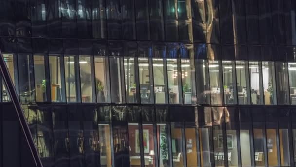 夜間のオフィスビルの窓が経過し 高層ビルのパノラマの窓からの光 輝く作業空間を持つ街の夜の風景 — ストック動画