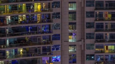 Dışarıdaki apartmanın gece manzarası renkli zaman çizelgesi. Pencere ve balkonlarında parlayan ışıklar olan yüksek gökdelen