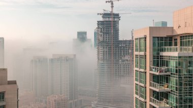Dubai gökdelenleri güneş doğarken şantiyeli iş sahasında sabah sisi ile kaplıydı. Birleşik Arap Emirlikleri 'nin şehir merkezinden hava görüntüsü.