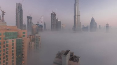Sabahın erken saatlerinde, sisli bir gecede Dubai şehrinin hava görüntüsü. Gökdelenleri ve inşa halindeki kuleleri olan gelecekçi şehir gökdelenleri
