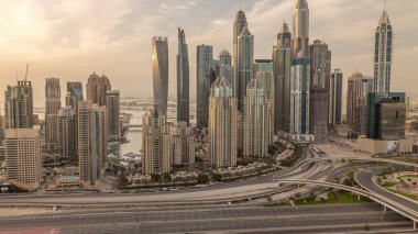 Dubai Marina highway intersection spaghetti junction evening . Tallest skyscrapers with reflection of sun on a glass surface. Aerial top view from JLT district during sunset with cloudy orange sky