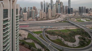 Panorama of Dubai Marina highway intersection spaghetti junction night to day transition . Illuminated tallest skyscrapers on a background. Aerial top view from JLT district before sunrise