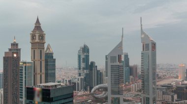 Skyscrapers on Sheikh Zayed Road and DIFC day to night transition  in Dubai, UAE. Towers in financial centre aerial view from above. Cloudy sky after sunset