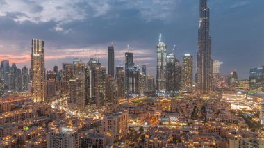 Dubai Downtown day to night transition  with tallest skyscraper and other towers around old town view from the top after sunset in Dubai, United Arab Emirates. Lights turning on.
