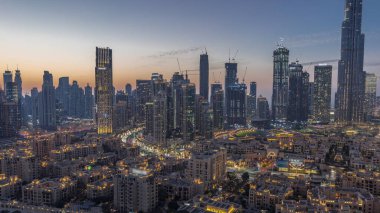 Close up view to Dubai's business bay towers aerial day to night transition . Rooftop view of some skyscrapers and new towers under construction after sunset