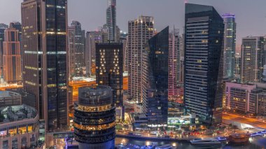 Dubai Marina Skyline with JLT district skyscrapers on a background aerial night to day transition . Illuminated towers with glass surface before sunrise