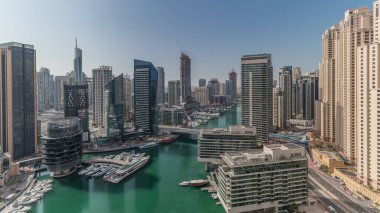 Panorama showing aerial view to Dubai marina skyscrapers around canal with floating boats and jlt with jbr districts . White boats are parked in yacht club