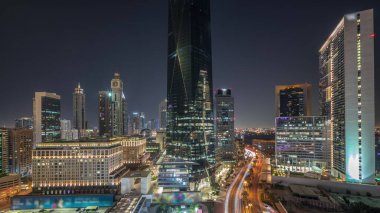 Dubai International Financial district during all night . Panoramic aerial view of business office towers with lights turning off. Illuminated skyscrapers with hotels near downtown