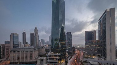 Dubai International Financial district night to day transition . Panoramic aerial view of business office towers before sunrise. Illuminated skyscrapers with hotels near downtown