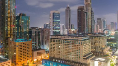 Dubai International Financial district night to day transition . Aerial view of business office towers before sunrise. Illuminated skyscrapers with hotels near downtown