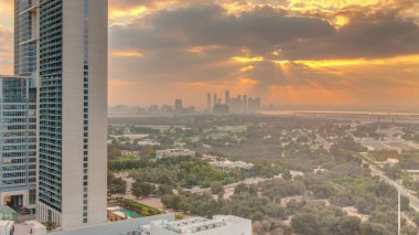 Sunrise over garden in Zabeel district with skyscrapers on a background aerial  in Dubai, UAE. Orange clouds on the sky with rays of sun light