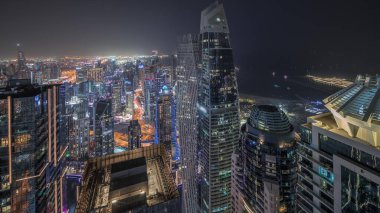 Panorama showing JBR district and Dubai Marina with JLT. Traffic on highway between skyscrapers aerial night . Illuminated modern towers and construction site