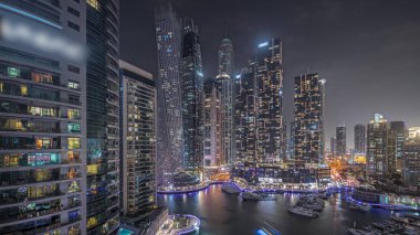 Panorama showing Dubai marina tallest skyscrapers and yachts in harbor aerial night . View at apartment buildings, hotels and office blocks, modern residential development of UAE
