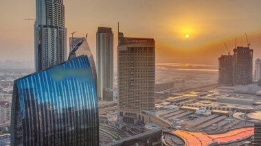 Aerial sunrise panorama of Downtown Dubai with shopping mall and traffic on a street morning  from above, UAE. Modern skyscrapers and hotels. Orange sky