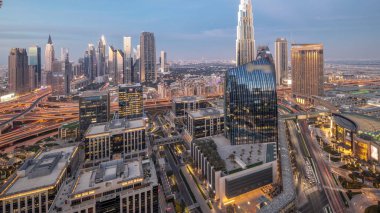 Futuristic Dubai Downtown and finansial district skyline panorama aerial day to night transition . Many illuminated towers and skyscrapers with traffic on streets