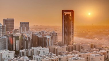 Sunrise over skyscrapers in Barsha Heights district and low rise buildings in Greens district aerial . Dubai skyline with orange sky at morning with desert on a background