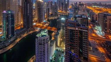 View of various skyscrapers in tallest recidential block in Dubai Marina aerial night to day transition panoramic  with artificial canal. Many towers in JBR district and yachts before sunrise