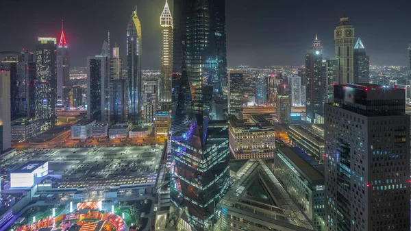 Panorama showing futuristic skyscrapers in financial district business center in Dubai on Sheikh Zayed road night . Aerial view from above with illuminated towers