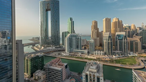 Panorama showing Dubai Marina skyscrapers and JBR district with luxury buildings and resorts aerial . Waterfront with palms and boats floating in canal