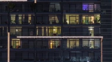 Çok katlı cam binaların panoramik pencerelerindeki çok renkli ışıkların düz gece panoraması. Büyük bir şehirde aydınlık bir gökdelen.