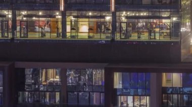 Çok katlı binaların camlarında çok renkli ışıklardan oluşan düz bir panorama. Büyük bir şehirde aydınlık bir gökdelen.