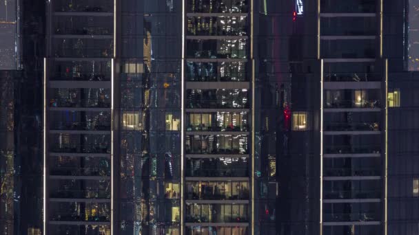 夜のタイムラプスでハイクラスの建物のアパートで照明されたパノラマの窓 超高層ビルの上に光る光 — ストック動画