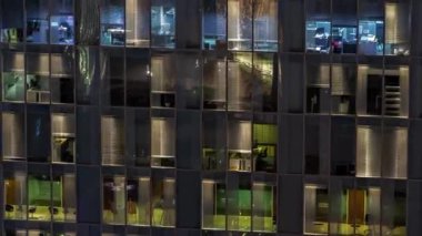 Aydınlatılmış çalışma odaları zaman ayarlı cam panoramik pencere cephesinin gece hava görüntüsü. Gökdelende parlayan ışık