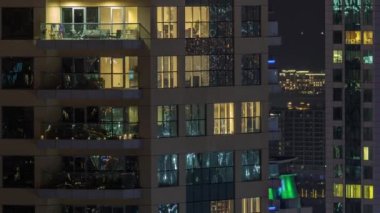 Parlak panoramik pencereli dış apartman binasının gece görüşü. Işıklı gökdelenle aydınlatılmış yüksek bir gökdelen