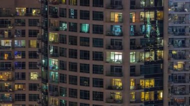 Dışarıdaki apartmanın akşam manzarası. Parlayan pencereleri olan bir bina. Işıklı gökdelenle aydınlatılmış yüksek bir gökdelen