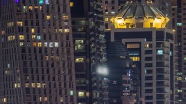 Parlak pencereli, dış apartman manzaralı bir zaman çizelgesi. Dubai marinasında ışıkları olan gökdelenler.